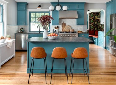 teal kitchen with natural wood floors, tan chairs, and gray walls