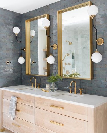 gray-blue tile backsplash with brass fixtures and wall sconces