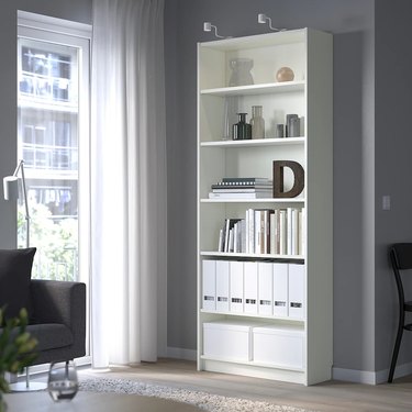 The IKEA Billy Bookcase in white filled with books, vases, and other knickknacks.