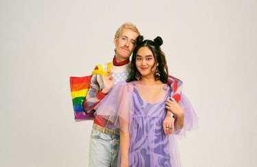 Two people smiling while holding rainbow IKEA Pridebags