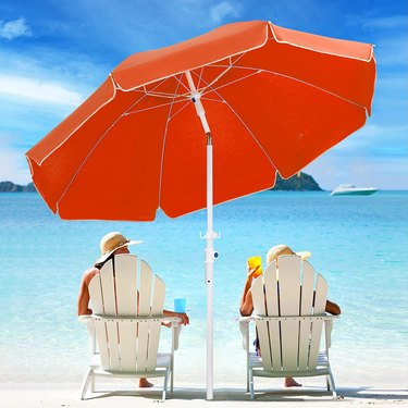 two people on beach under red umbrella