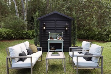 Black painted shed with lanterns serving as cocktail lounge area outside