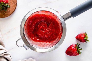 Strawberry puree in a fine mesh strainer