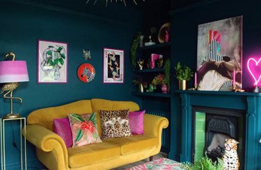 Teal room with mustard yellow couch, pink pillows.