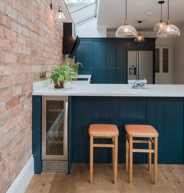Teal kitchen, brick wall, white counters.