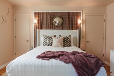 A bedroom with a brown plaid headboard, a white bed, and a plum-colored throw.