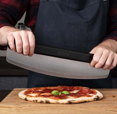 man cuts pizza with a rocker blade