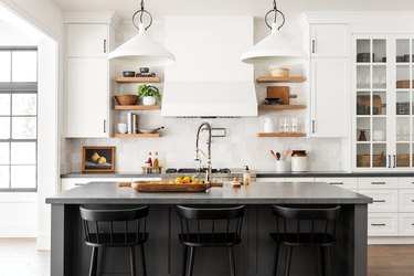 elevated farmhouse kitchen with black island and white cabinets