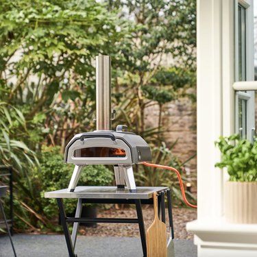 Ooni Karu 12G pizza oven sits on a table in the backyard