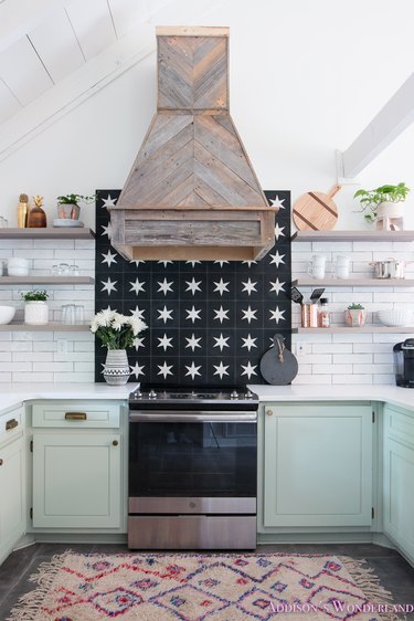 mint green kitchen cabinets with black and white backsplash