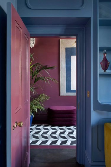 An open doorway leading from a room painted blue into a room painted plum.