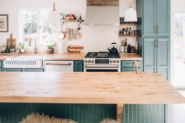 teal kitchen cabinets with wood countertop in bohemian kitchen