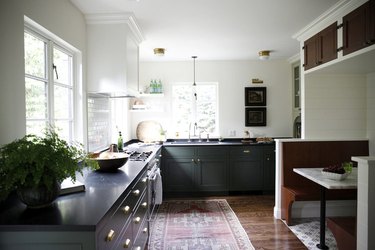 Green kitchen cabinets with brass pulls and white walls