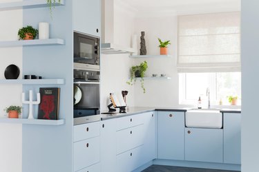Light blue kitchen cabinetry with black countertop and white walls