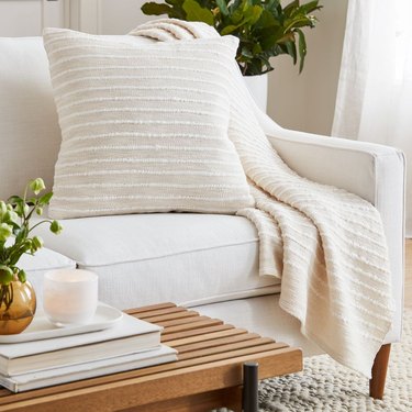 Cream colored throw and pillow on a white couch