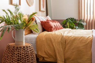 bed with yellow quilt surrounded by plants