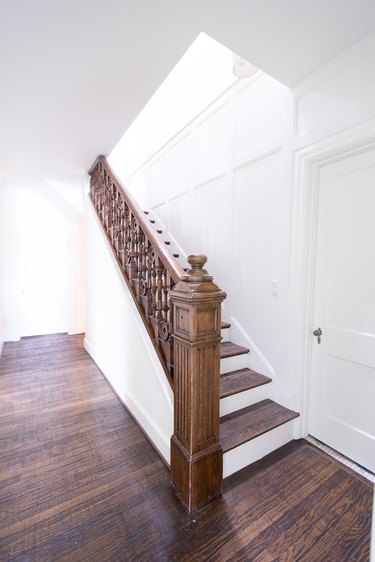 A stairway with dark wood in a rood with white paneled walls.