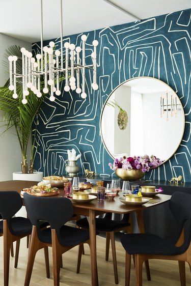 dining room with teal wall, black chairs, and gold accents