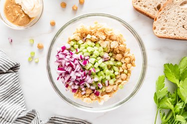 smashed chickpeas, diced onion, and diced celery in glass bowl