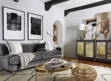 Gray couch in white walled room with black and white framed art above it.