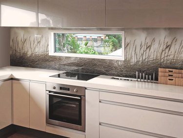 Glass backsplash with design, white cabinets, white counters.