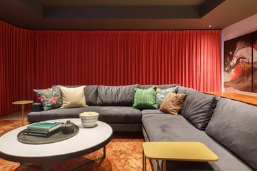 Home theater with red curtains and charcoal gray couch