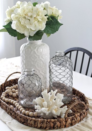 centerpiece in seagrass basket with piece of coral and vase of hydrangeas