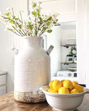 bowl of lemons and ceramic jug of flowers on wooden table