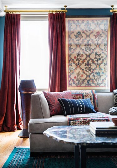 A teal living room with burgundy curtains and vintage accents.