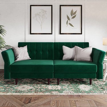 Green mid-century couch in room with green oriental carpet