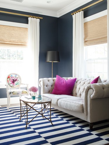 A navy living room with white curtains.