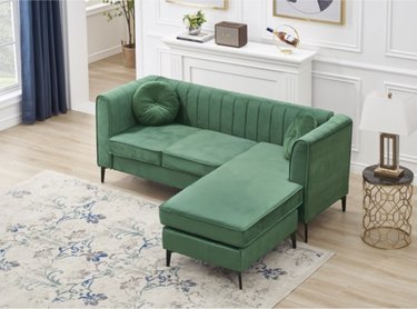 green couch in white room with beige rug