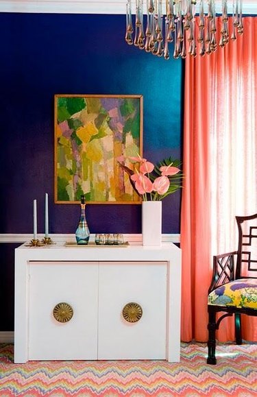 A jewel blue living room with coral curtians.