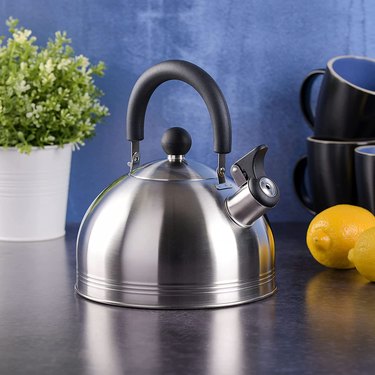 Metal kettle on counter with blue background