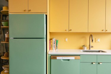 A green painted refrigerator and dishwasher and yellow upper cabinets