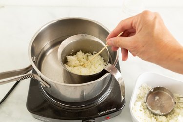 Melting candle wax in a pitcher in a pan with water