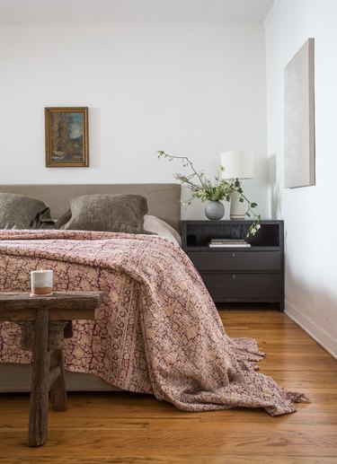 bed styled with extra long, patterned coverlet