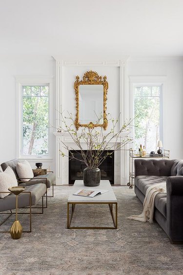 room with charcoal gray couch and gold mirror