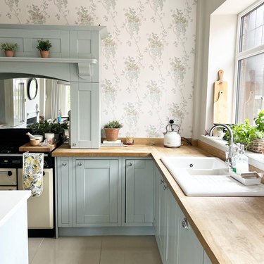 kitchen with sage green cabinets and botanical-print wallpaper