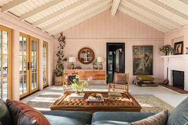 A-frame ceiling living room with earthy furniture, eclectic decor, and yellow French doors.