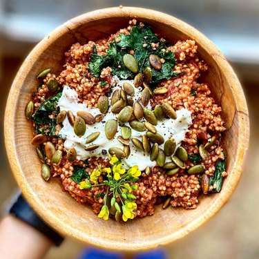 person holding a bowl with grains and veggies