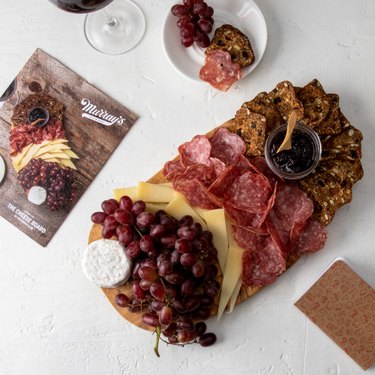 Charcuterie board with meat, fruits, crackers, and cheese