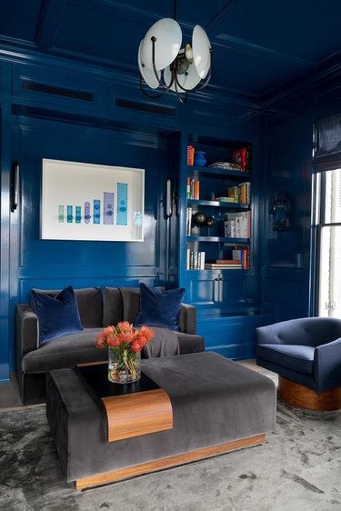 Glossy blue lacquered walls and ceiling invite a handsome appeal to a contemporary living room furnished with a charcoal velvet sofa a