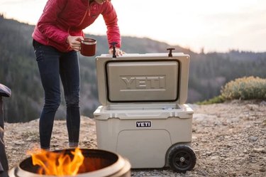 Woman with a yeti cooler by a campfire