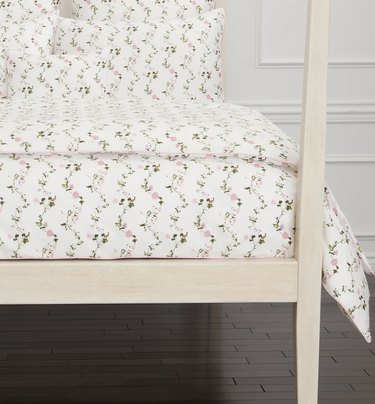 White cottagecore bedding with small pink flowers on a cream poster bed