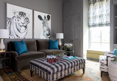 Charcoal gray sofa sofa, accented with bold blue pillows, is flanked by brown wooden end tables topped with ivory lamps.