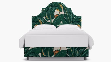 bed with white sheets and green leaf pattern bedframe