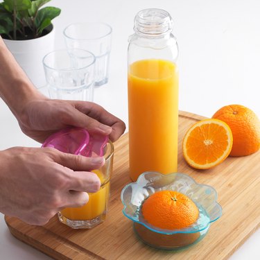 person with cover and orange juice nearby, along with oranges