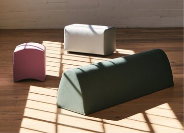 Three rounded, soft benches in sage, white, and pink.