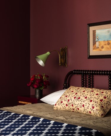 Maroon walls in bedroom against dark bedroom furniture and floral pillow
